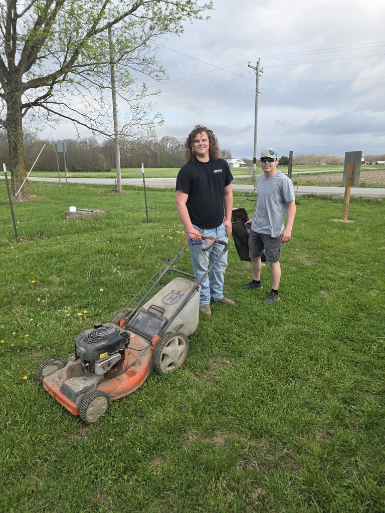 Two students are mowing the cemetery grass.