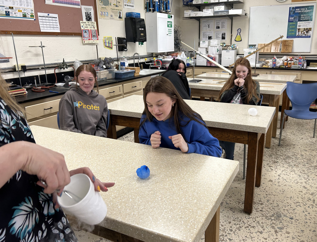 A teacher has added something to a balloon to make it shrink. A student is watching.