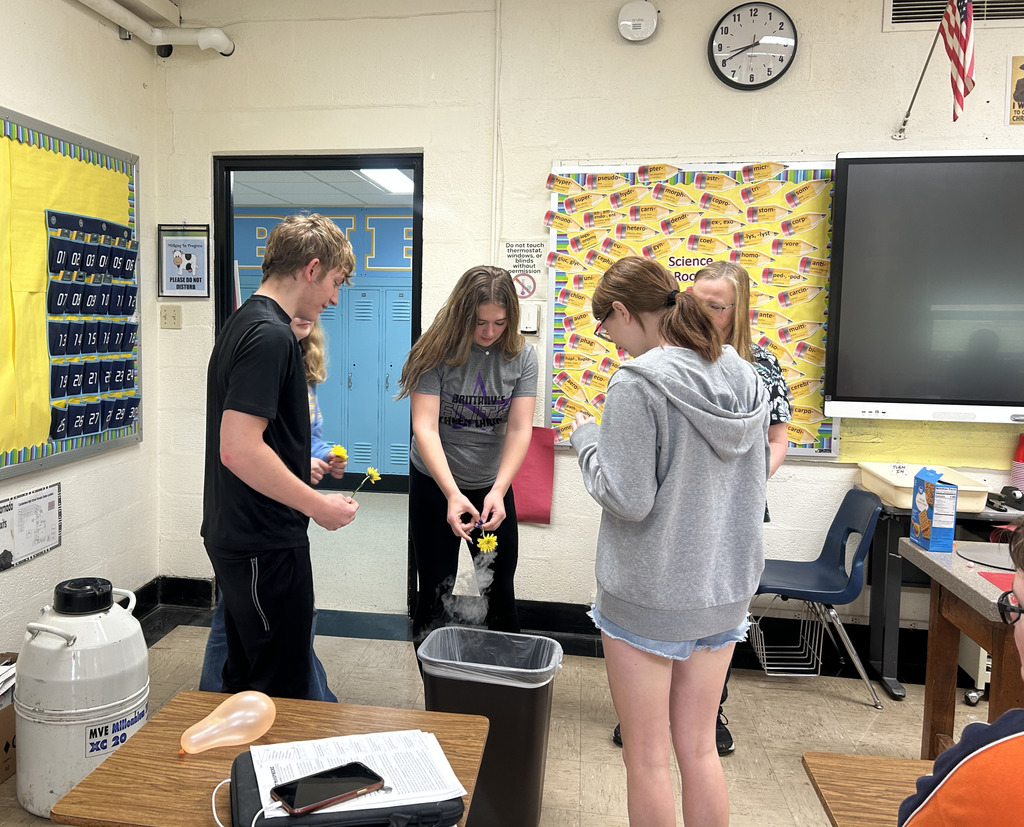 Students are working with a flower that is steaming. It is being held over a trash can.