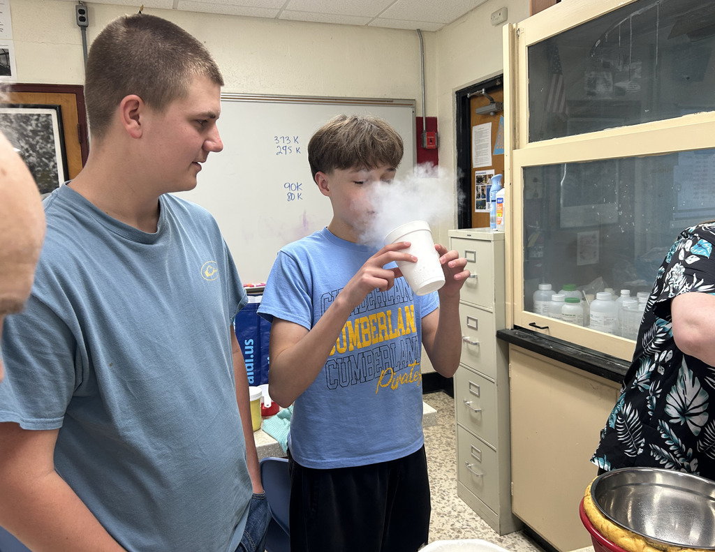 A student is holding a cup of steaming nitrogen.