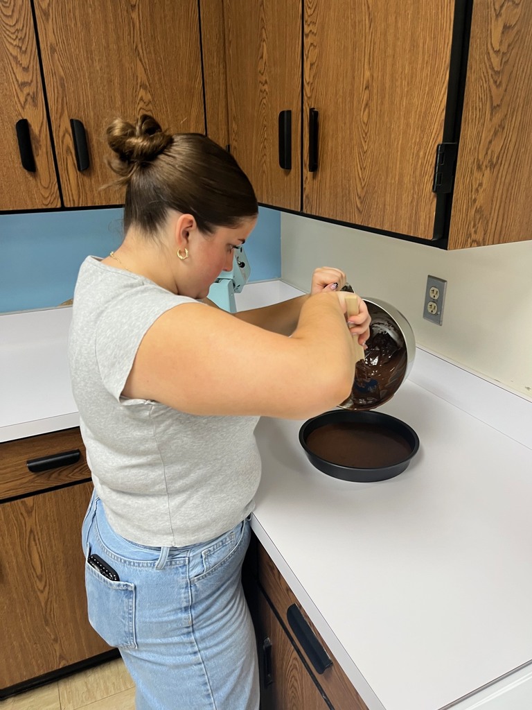 A student is pouring the batter into the pan. 