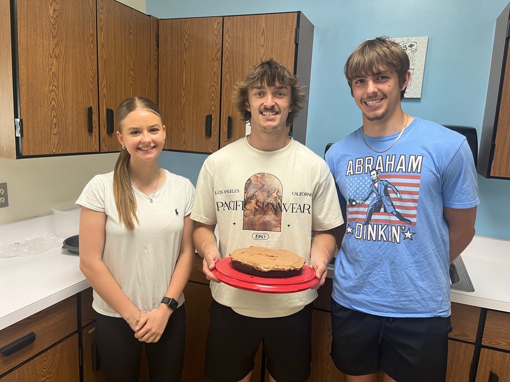 Three students are holding their iced chocolate cake. 