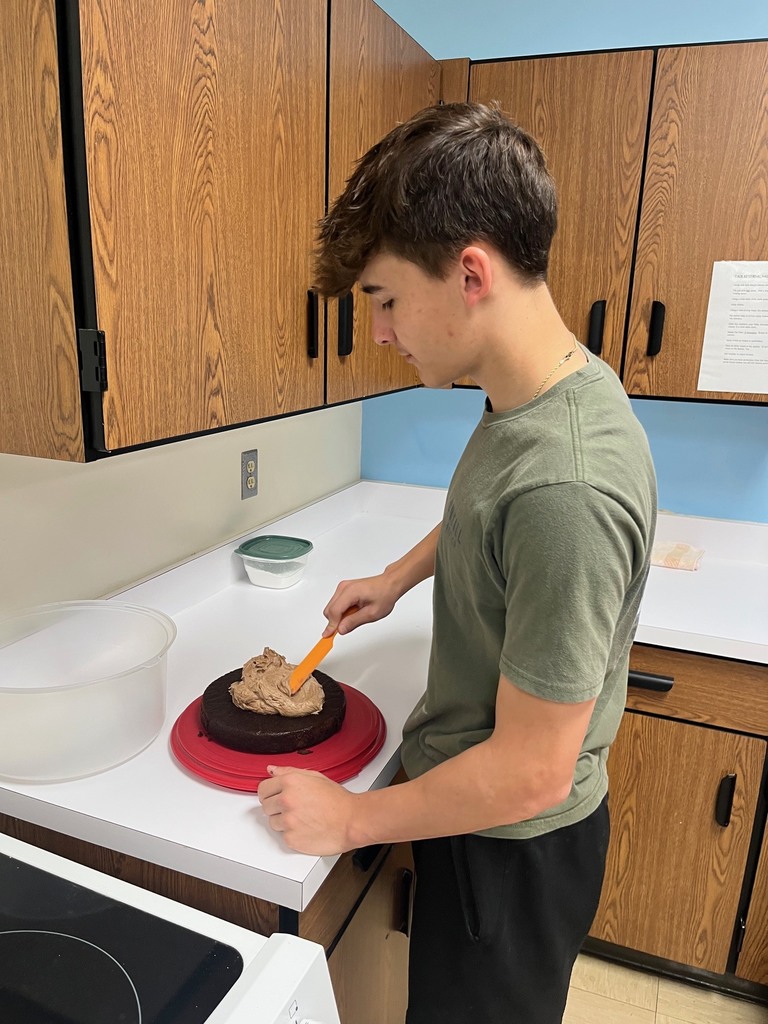 A student is icing a cake. 