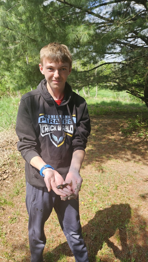 A student is holding a tadpole. 