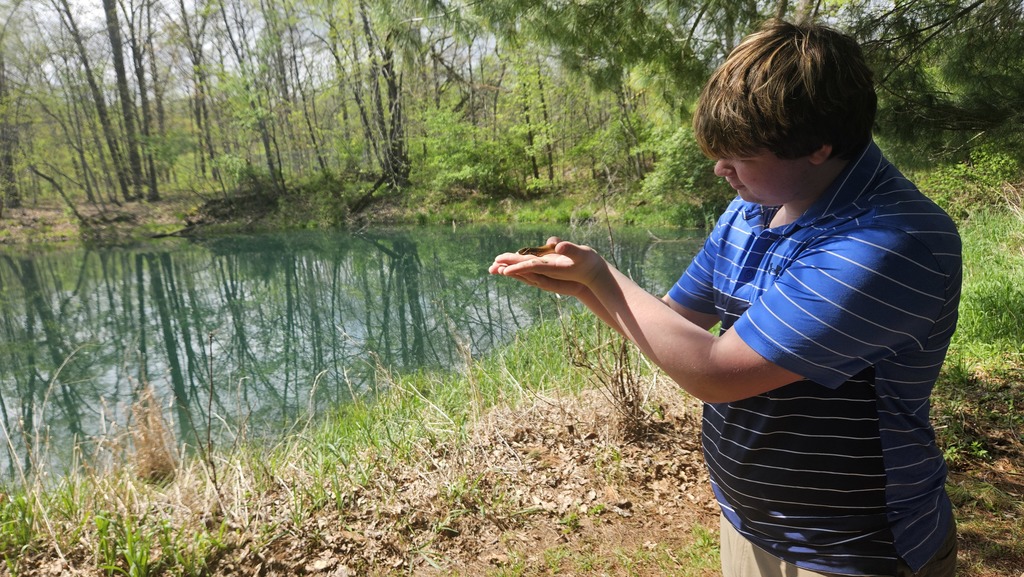 A student is holding a tadpole. 