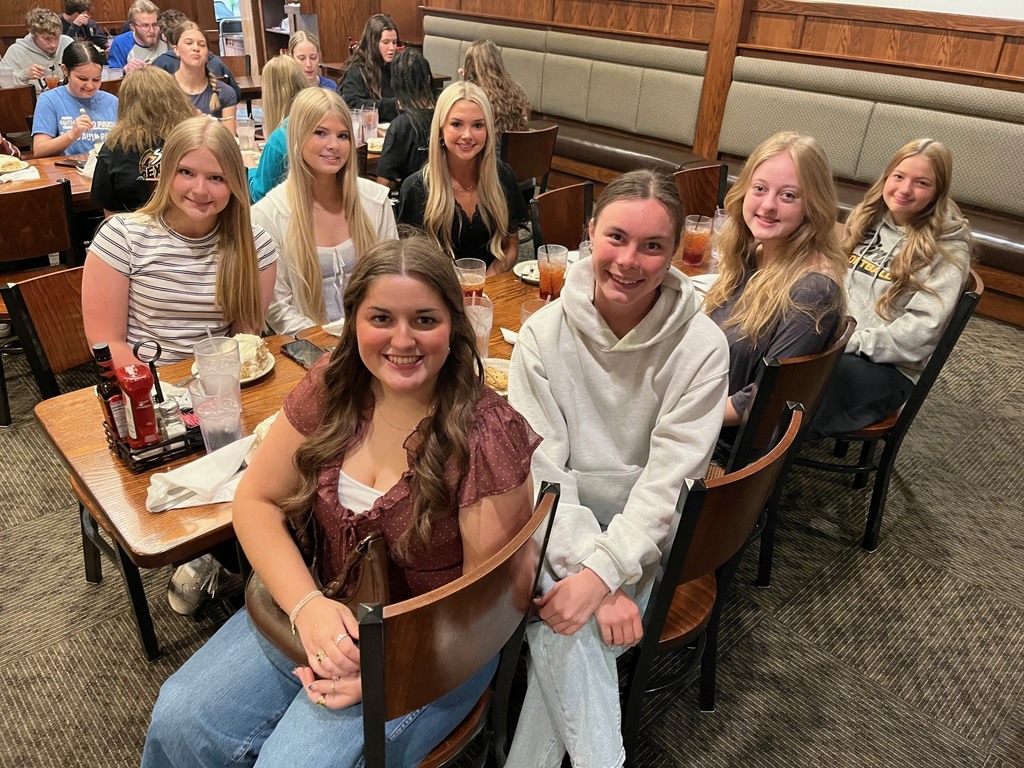Students are sitting at a dining table eating a dessert. 