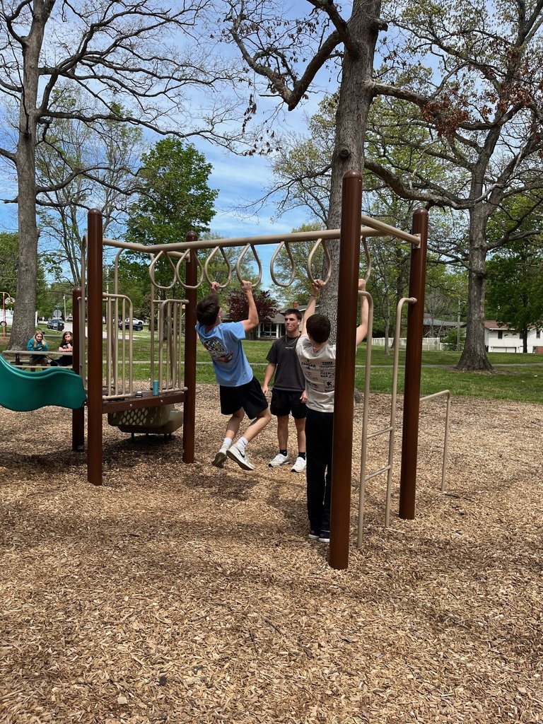 Three students are playing on the playground equiptment. 
