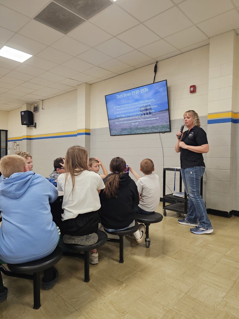 A speaker is using a microphone to talk to a group of students. 