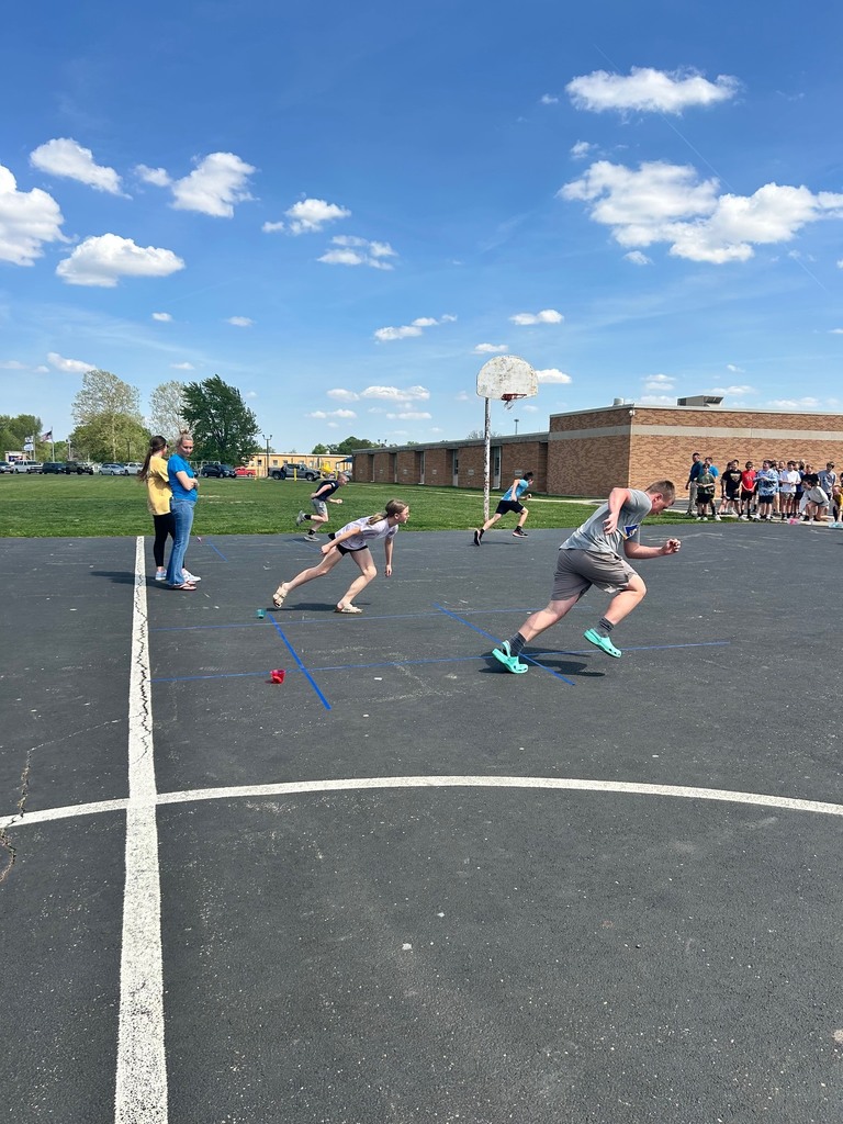 Two students are racing to the tic tac toe board to place their bean bag. 