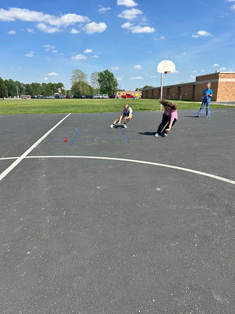 Two students are racing to the tic tac toe board to place their bean bag. 