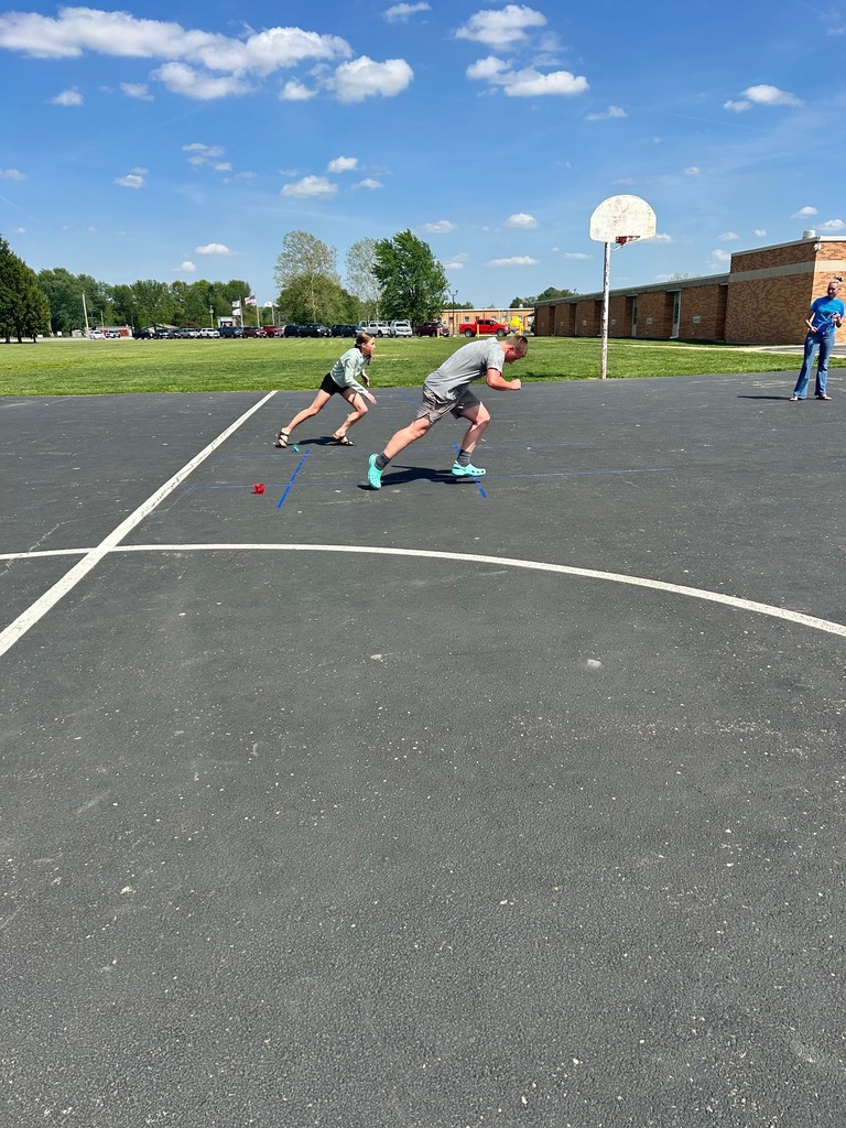 Two students are racing to the tic tac toe board to place their bean bag. 