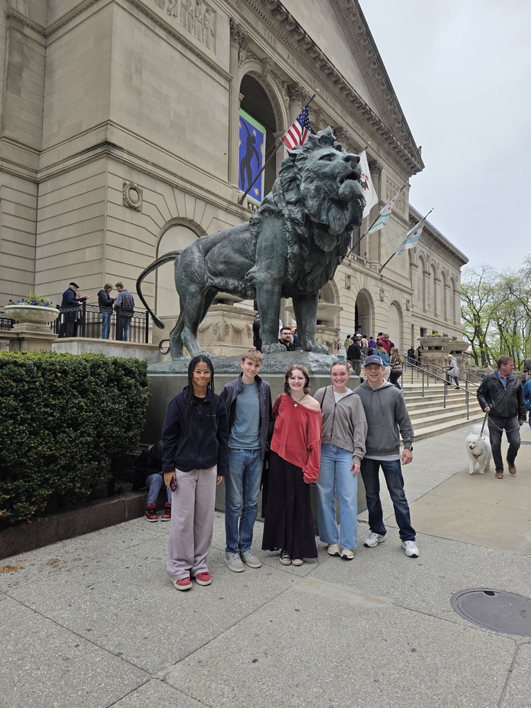 Five students are standing in front of a lion statue at the Art Museum.
