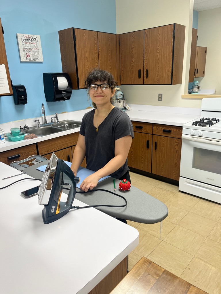 A studetn is ironing the material to be used for the project. 