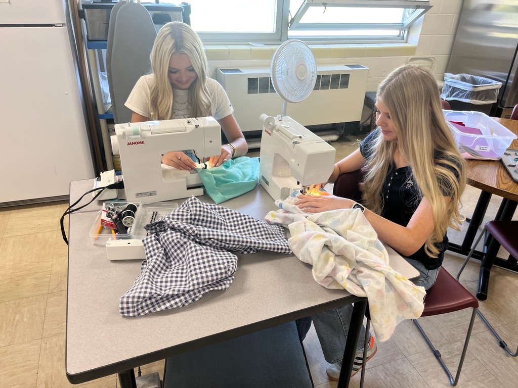 Two students are sewing on sewing machines. 