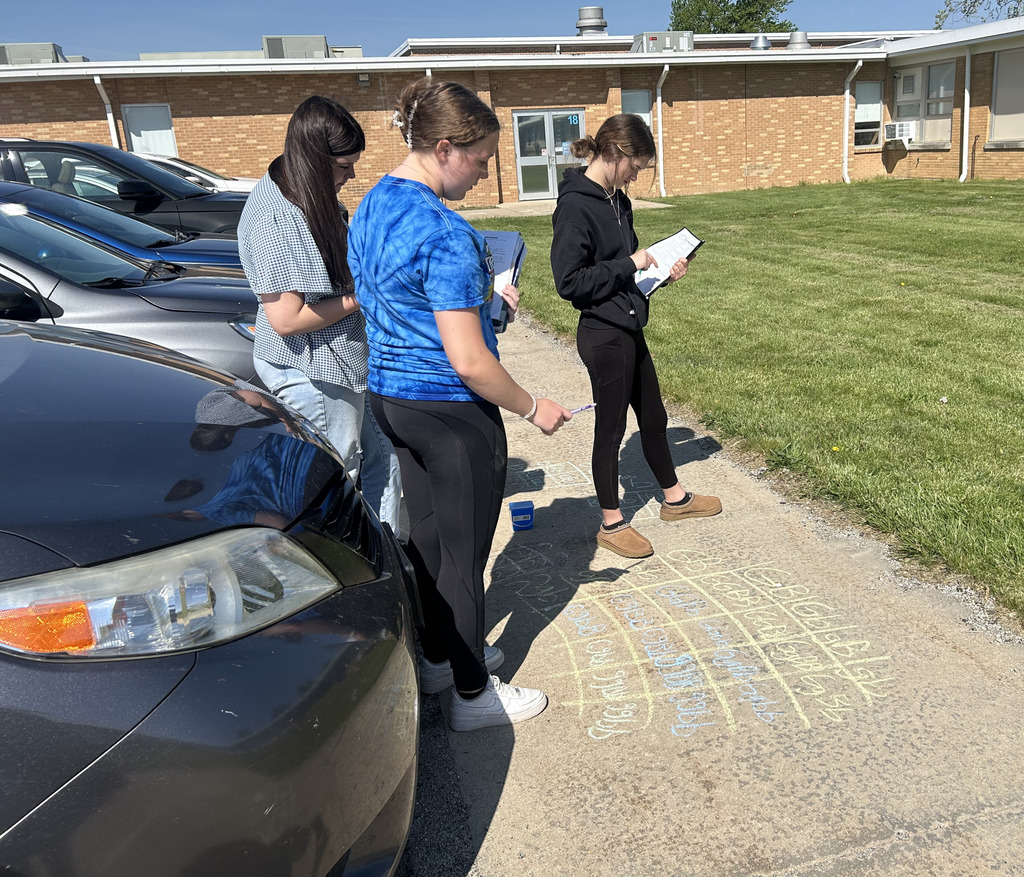 Two students are working on a Punnett square with sidewalk chalk.