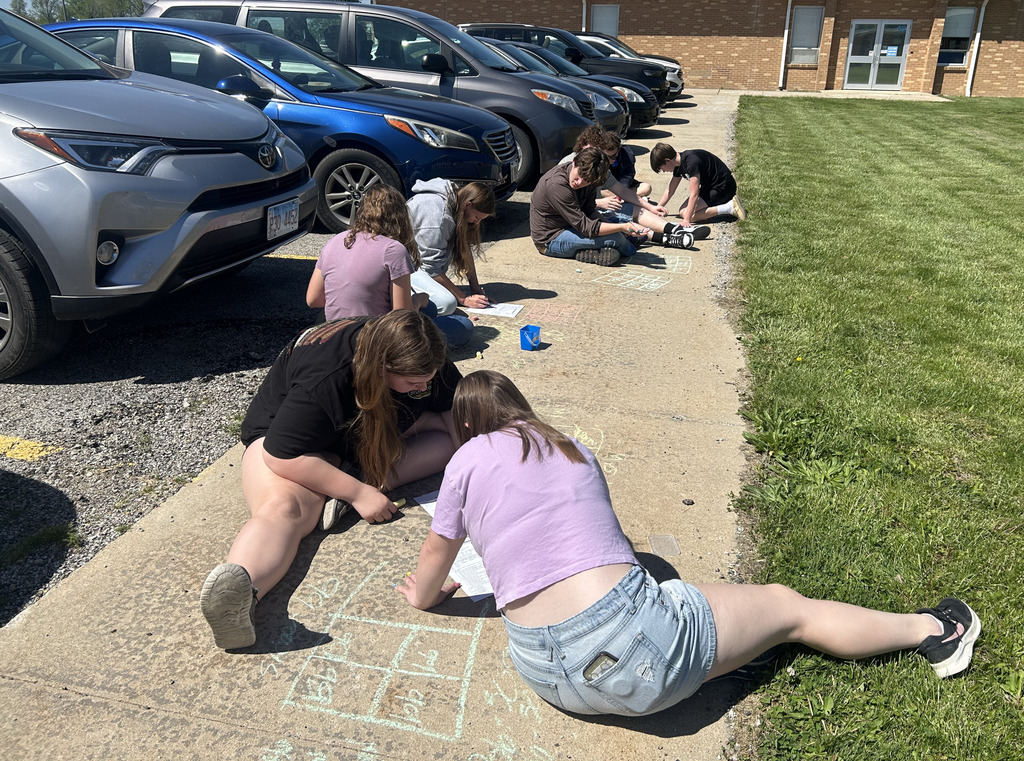 Students are working on a Punnett square with sidewalk chalk.