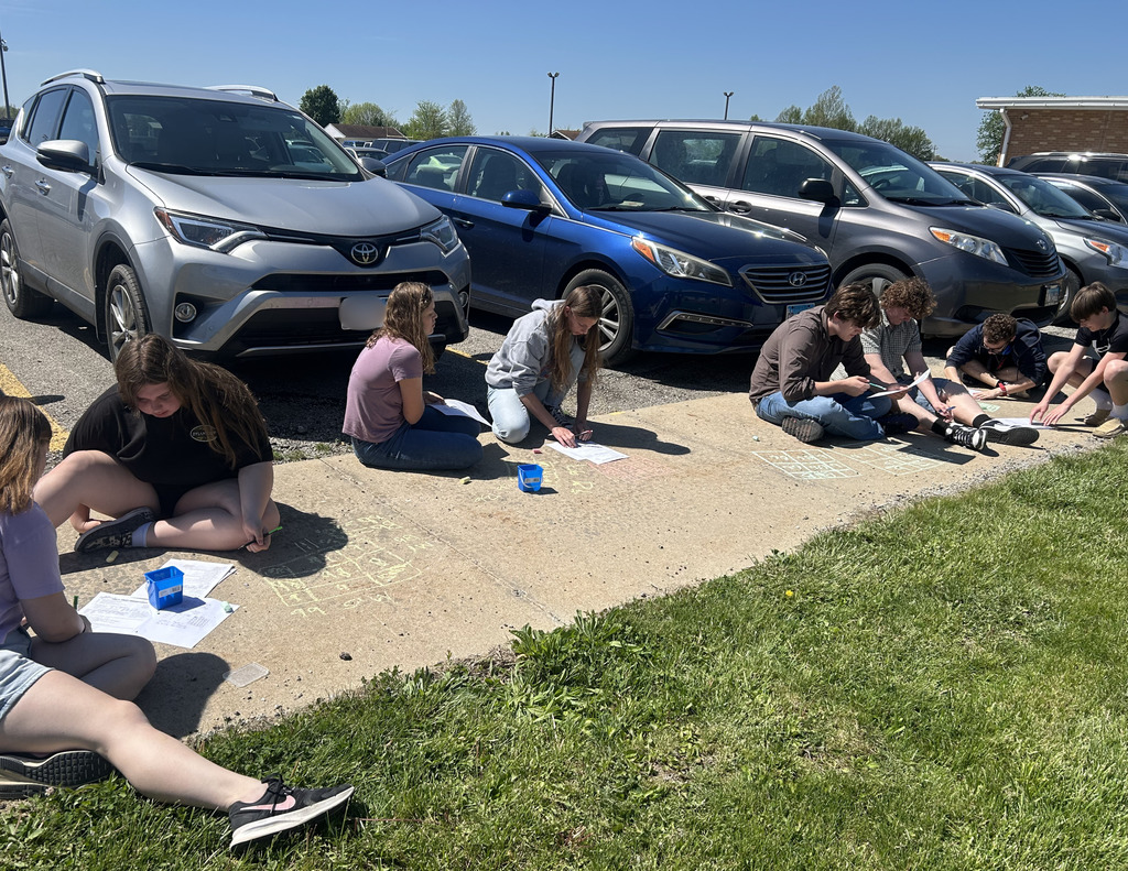 Students are working on a Punnett square with sidewalk chalk.
