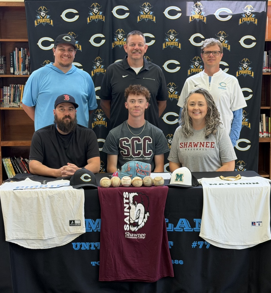 Pictured sitting at a table is GJ and his parents. Behind are the baseball coach, Athletic Director, and Principal. The table is decorated with jerseys, hats, and baseballs. 