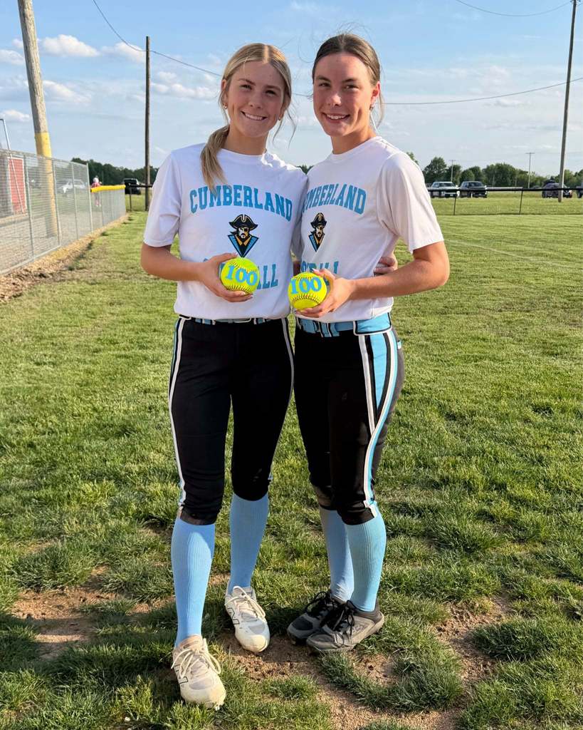AT and JC are standing together, each holding their 100th hit softball. 
