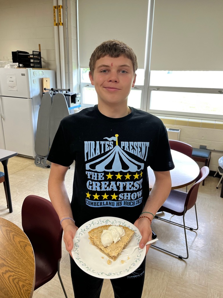 A student is holding a piece of apple pie. 
