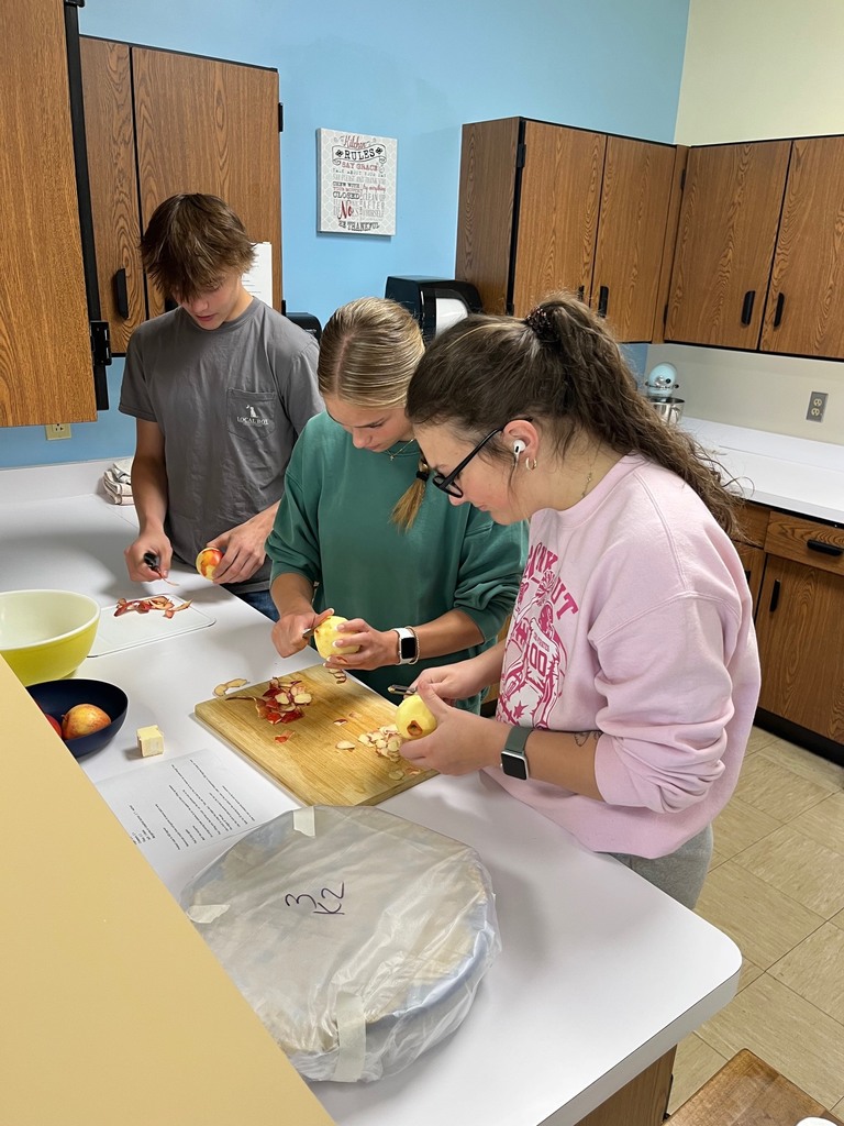 Three students are peeling apples. 