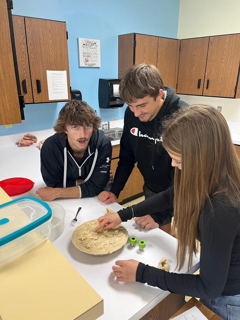Three students are placing stars made of dough on top of the crust. 