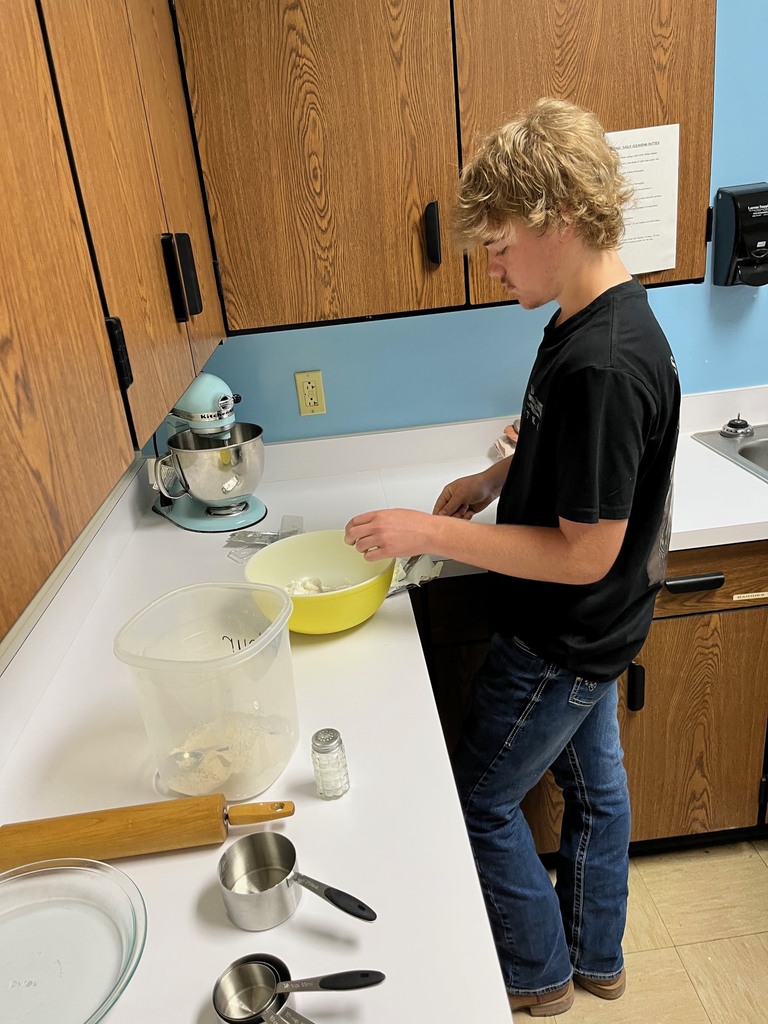 A student is adding ingredients to a bowl. 