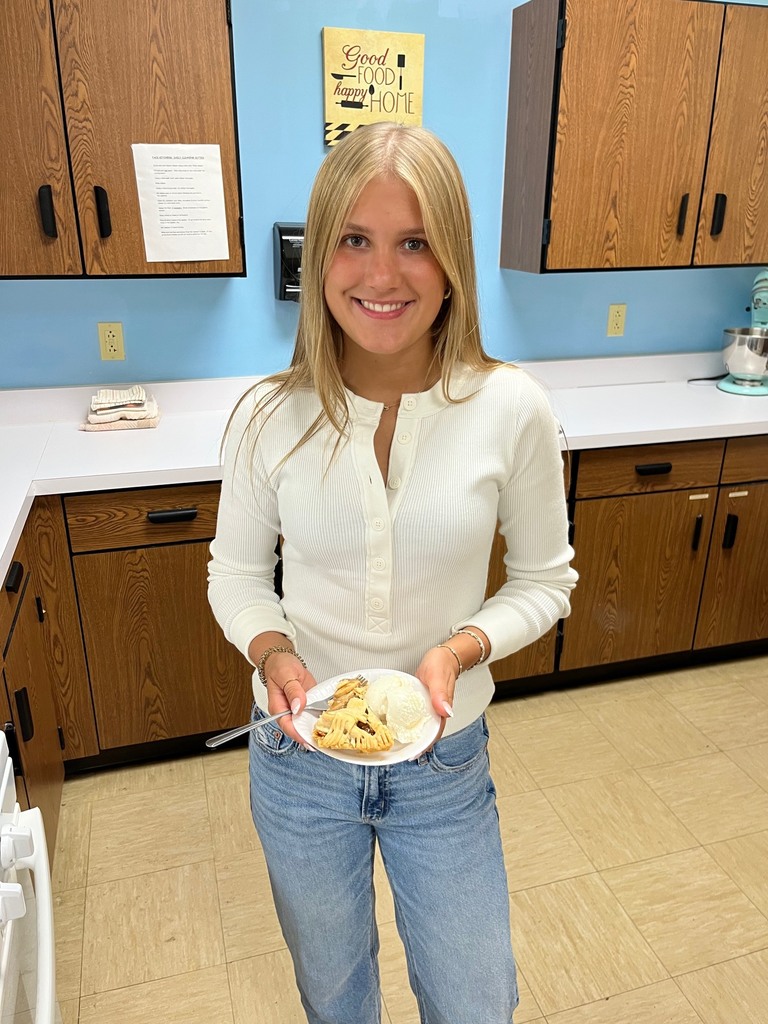 A student is holding a piece of apple pie. 