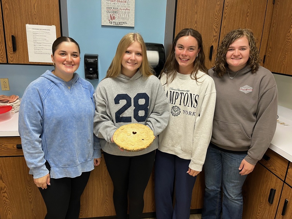 A group of four students is holding their finished pie. 
