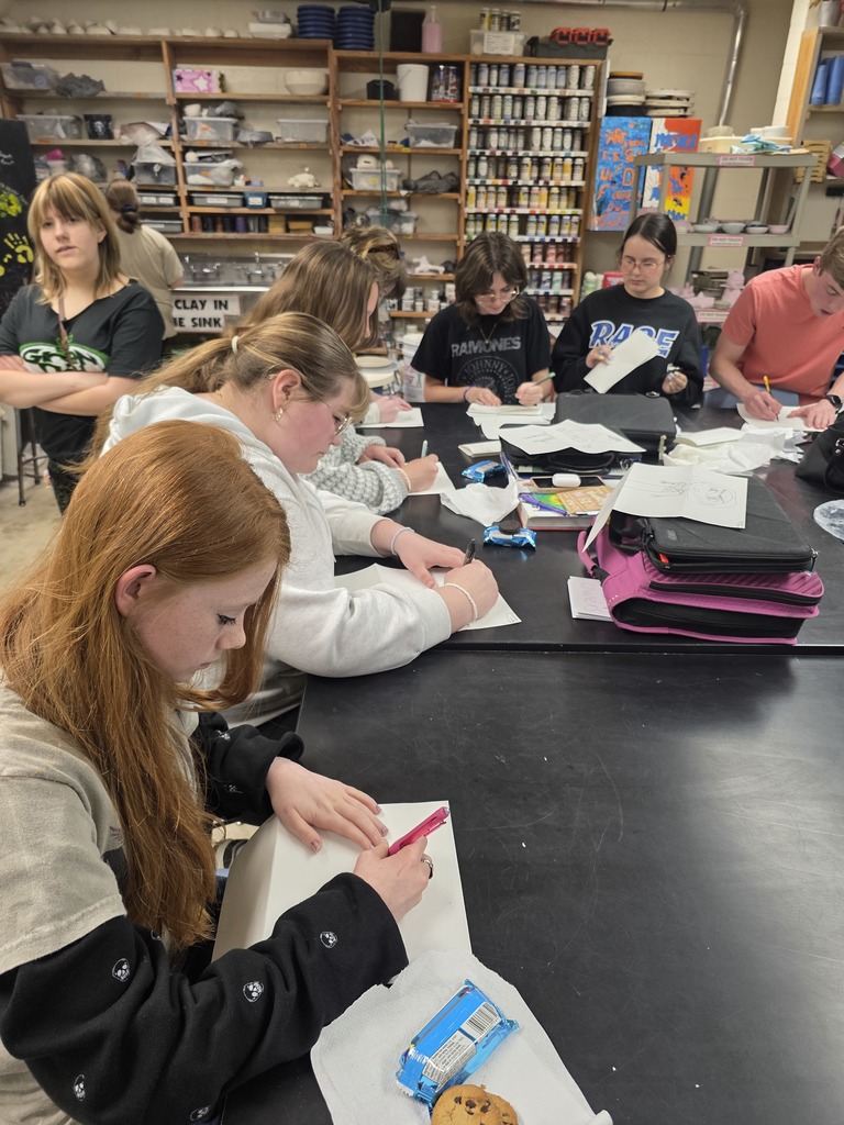 Students are sitting around a table working on their collaborative project. 