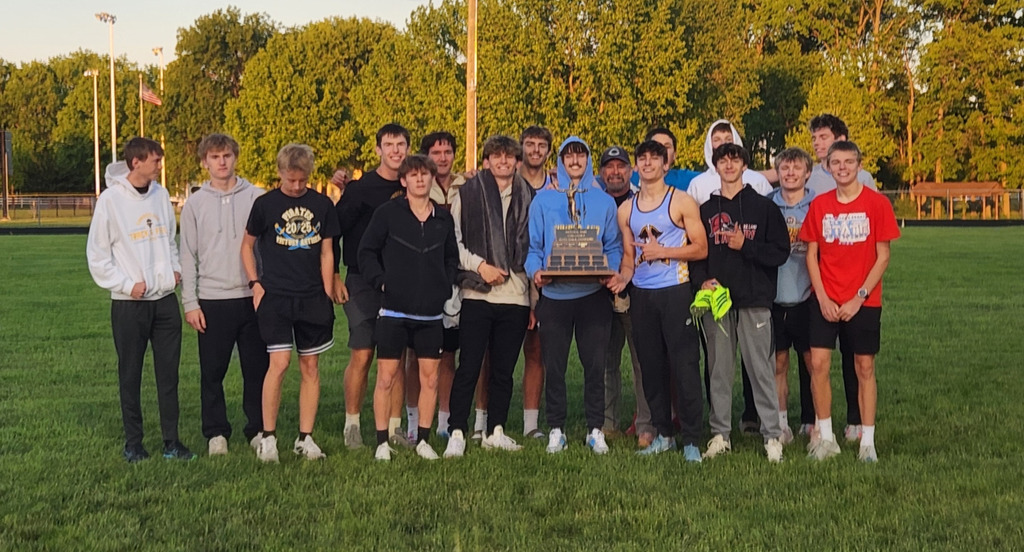 The boys team is standing together and holding the traveling trophy. 