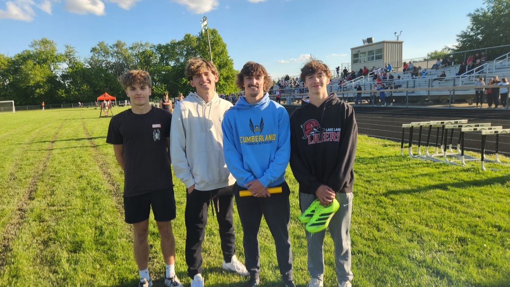 Four boys from one of the relay teams is standing together with their baton. 