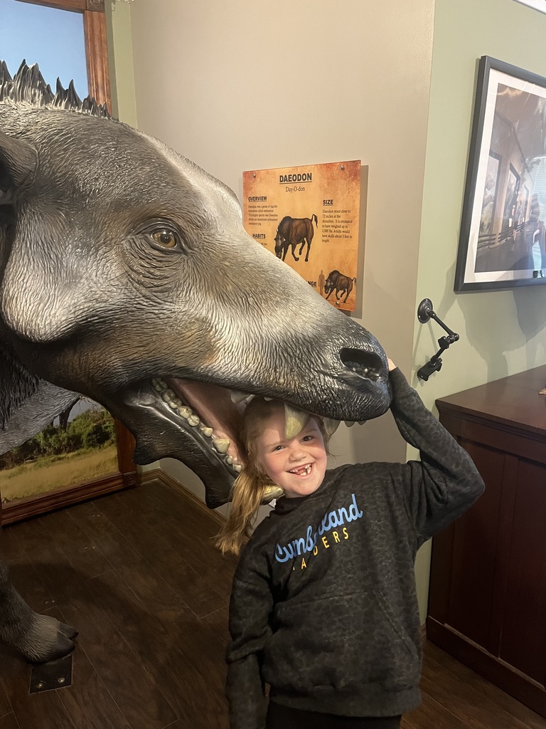 One student is standing with her head in a statue of a wild animal. 