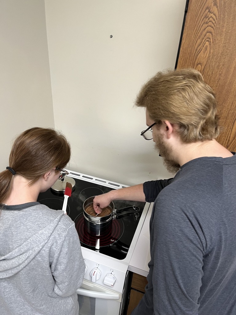 Two students are dipping the balls into chocolate. 