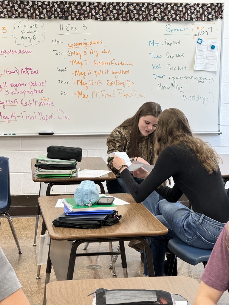 Two students are looking at each other's letters. 