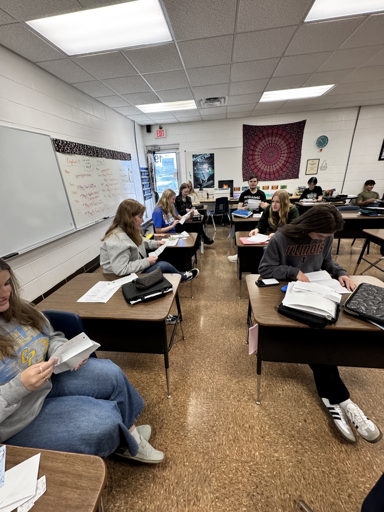 Students are sitting in their desks reading their letters. 