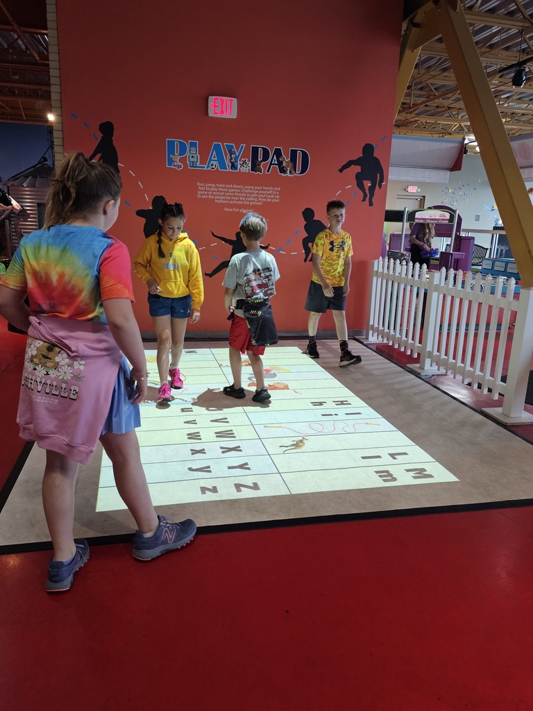 Four students are walking across the Play Pad. 