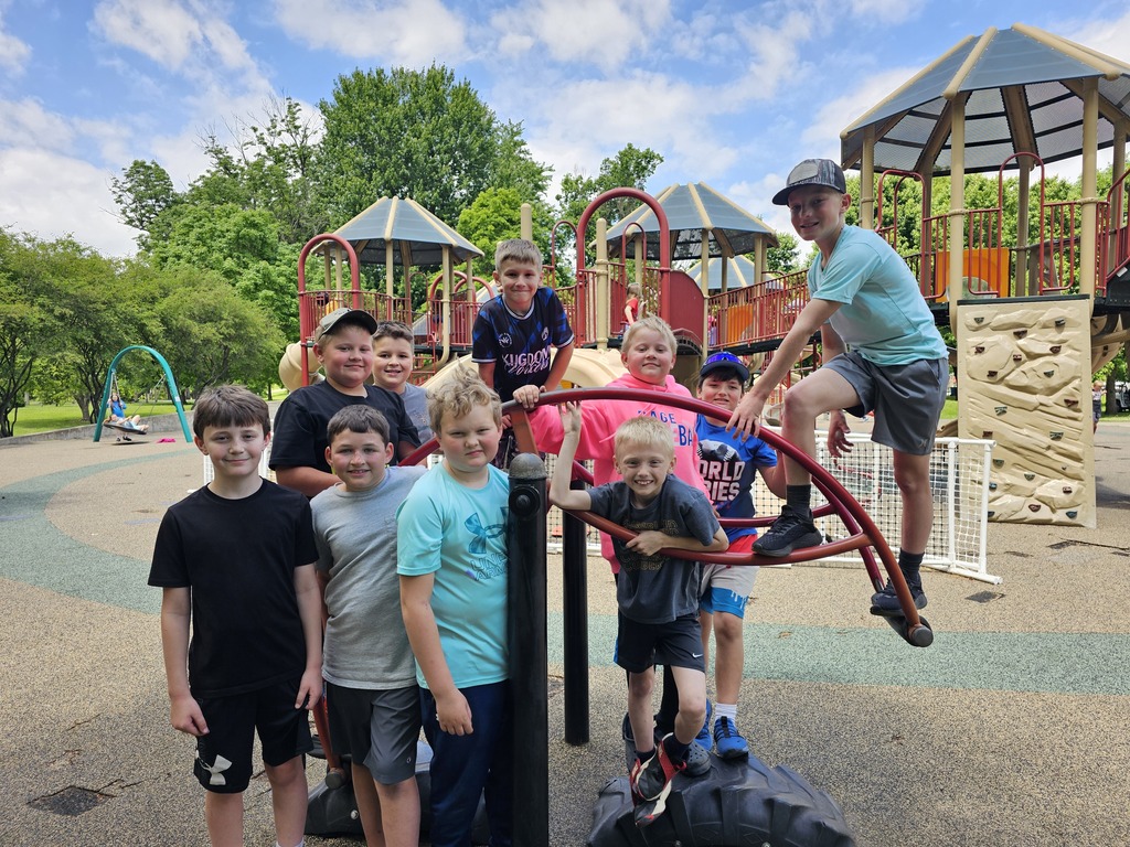 Several students are posing for a picture on a piece of park equiptment.