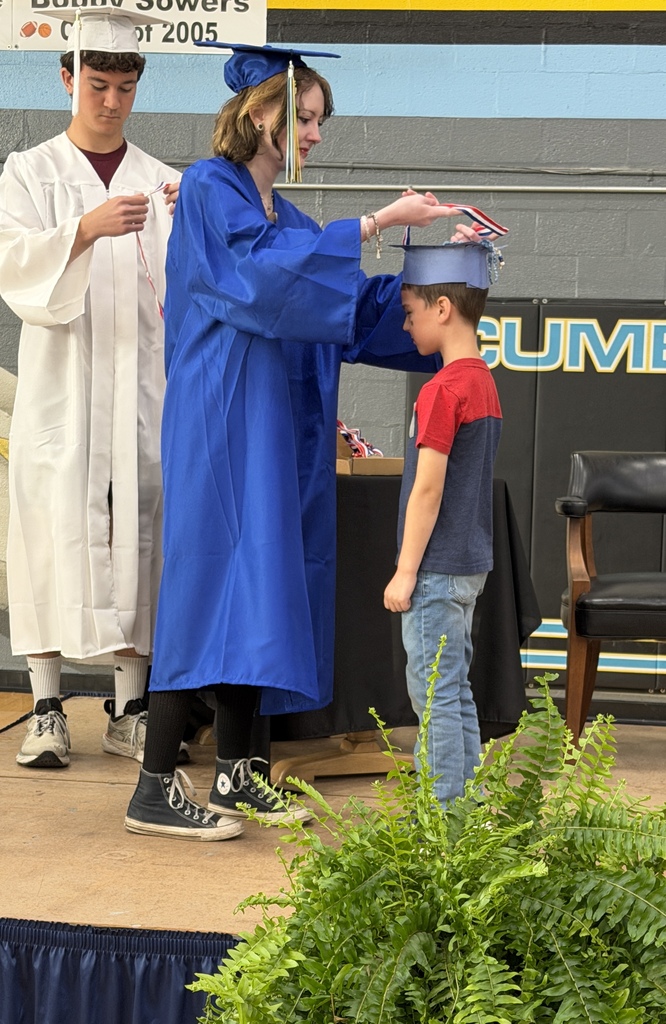 A senior student is placing a medal on a kidergarten student. 