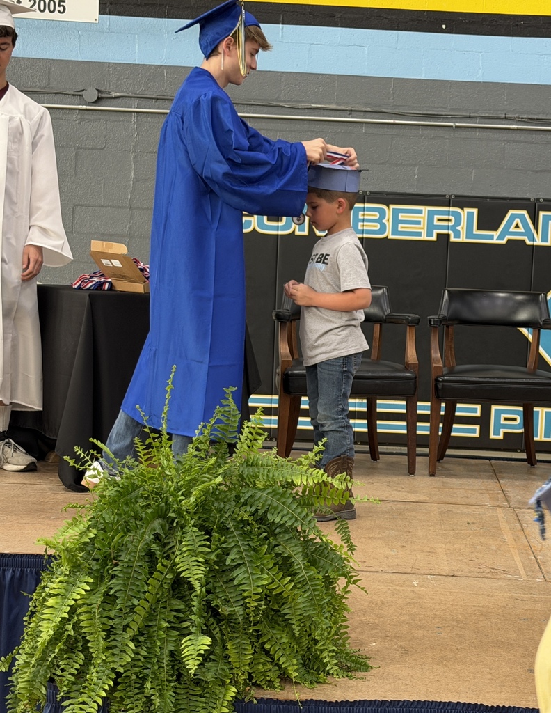 A senior student is placing a medal on a kidergarten student. 