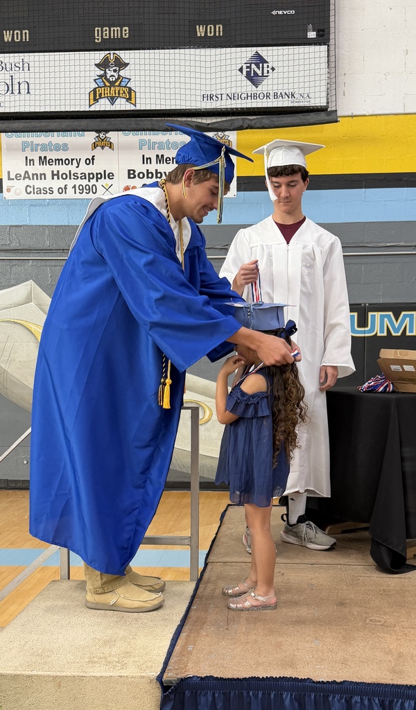 A senior student is placing a medal on a kidergarten student. 