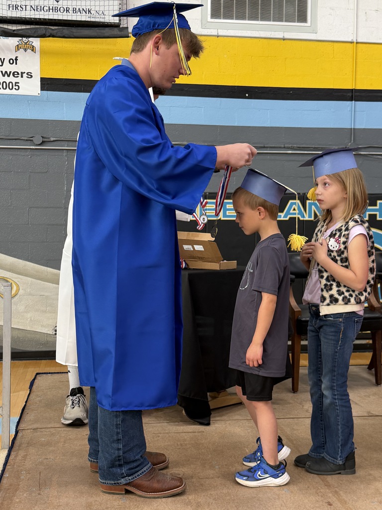 A senior student is placing a medal on a kidergarten student. 
