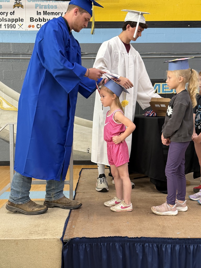 A senior student is placing a medal on a kidergarten student. 