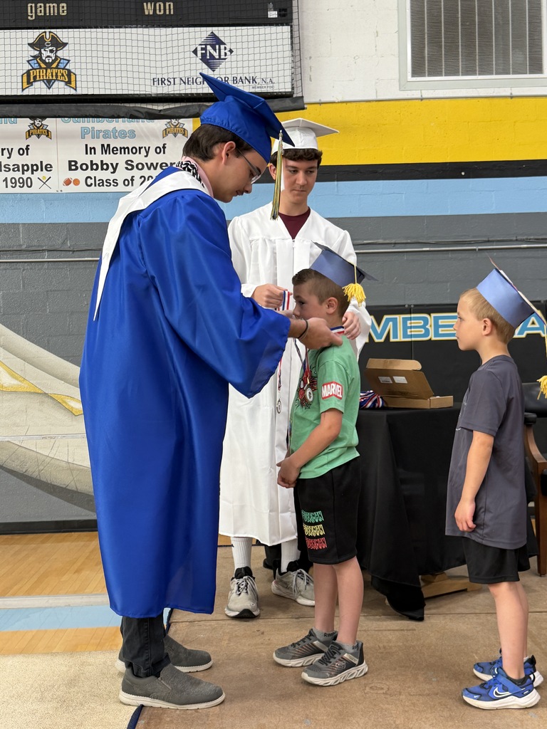 A senior student is placing a medal on a kidergarten student. 