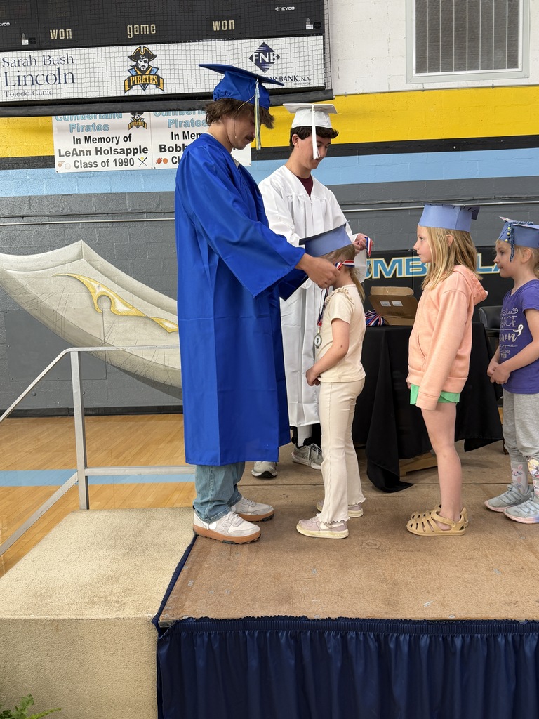 A senior student is placing a medal on a kidergarten student. 