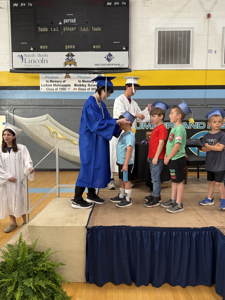 A senior student is placing a medal on a kidergarten student. 