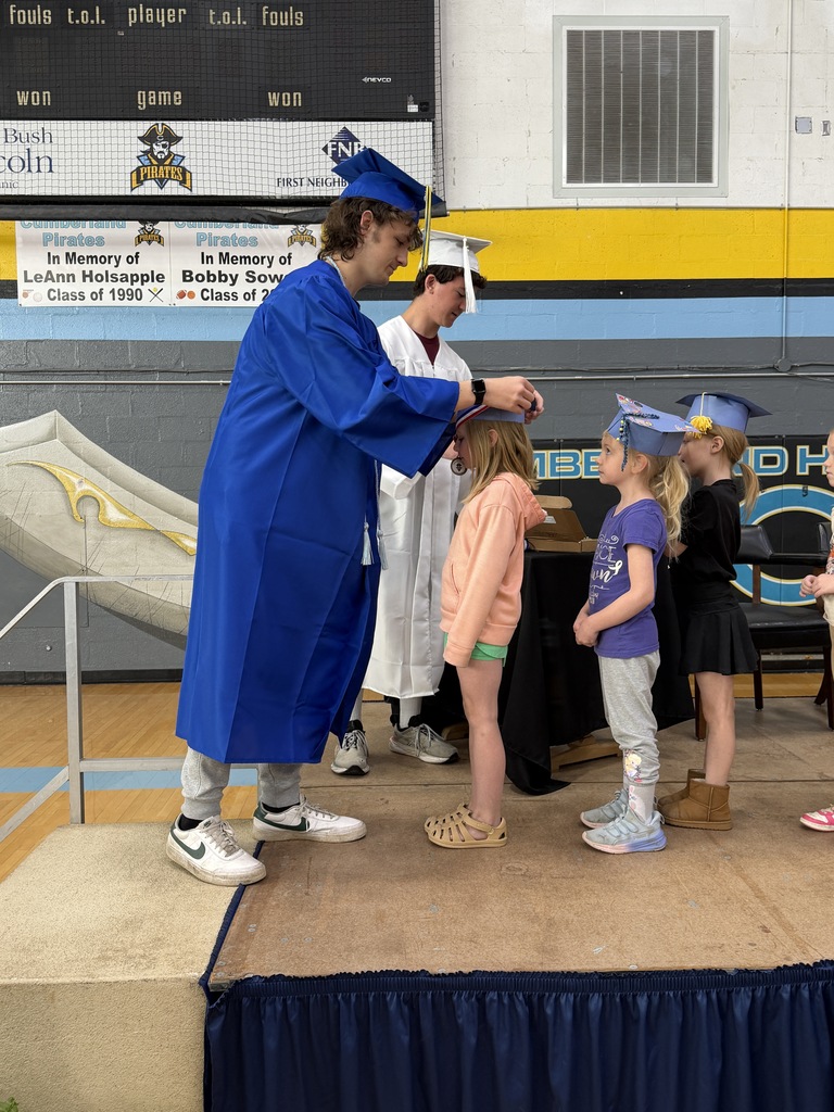 A senior student is placing a medal on a kidergarten student. 