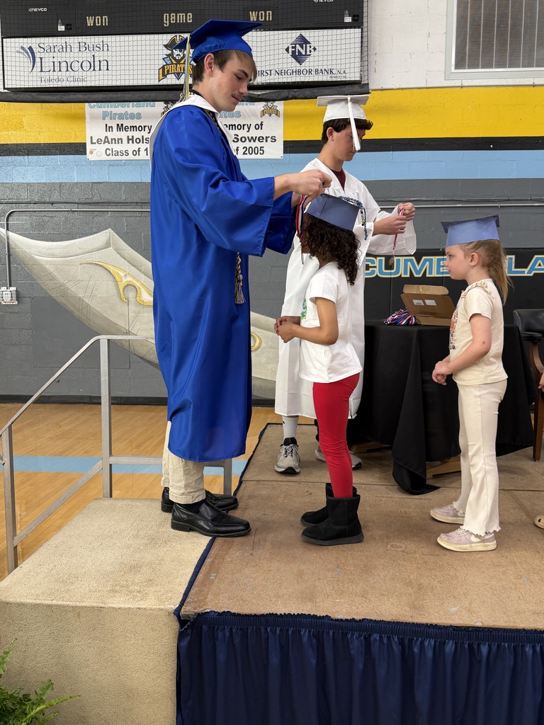 A senior student is placing a medal on a kidergarten student. 