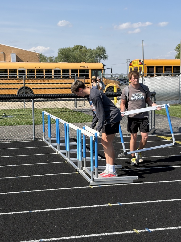 Two Cumberland students are setting up hurdles for a track meet. 