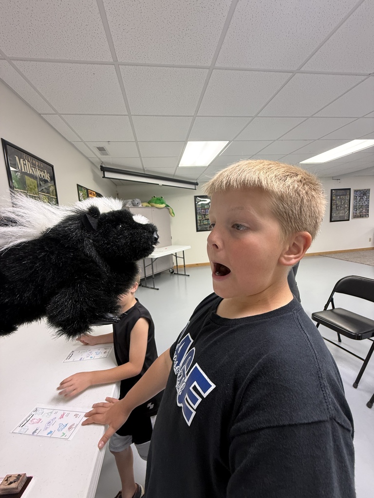 A student is showing a shocked face while looking at a skunk puppet. 